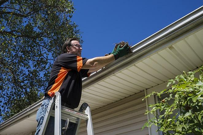 worker repairing damaged gutter on a residential roof in Beecher IL