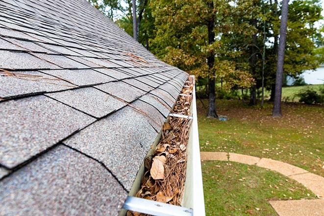 a gutter downspout being cleared of debris